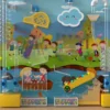 Colorful mural of kids playing in a park: slide, balls, trees, and a cheerful cloud on a bright playground wall.