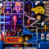 Colorful arcade machine panel with a cartoon orange robot, gears, tubes, and pulleys for interactive play.