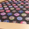 Collection of colorful, patterned spinning tops laid out on a black surface inside a wooden box.