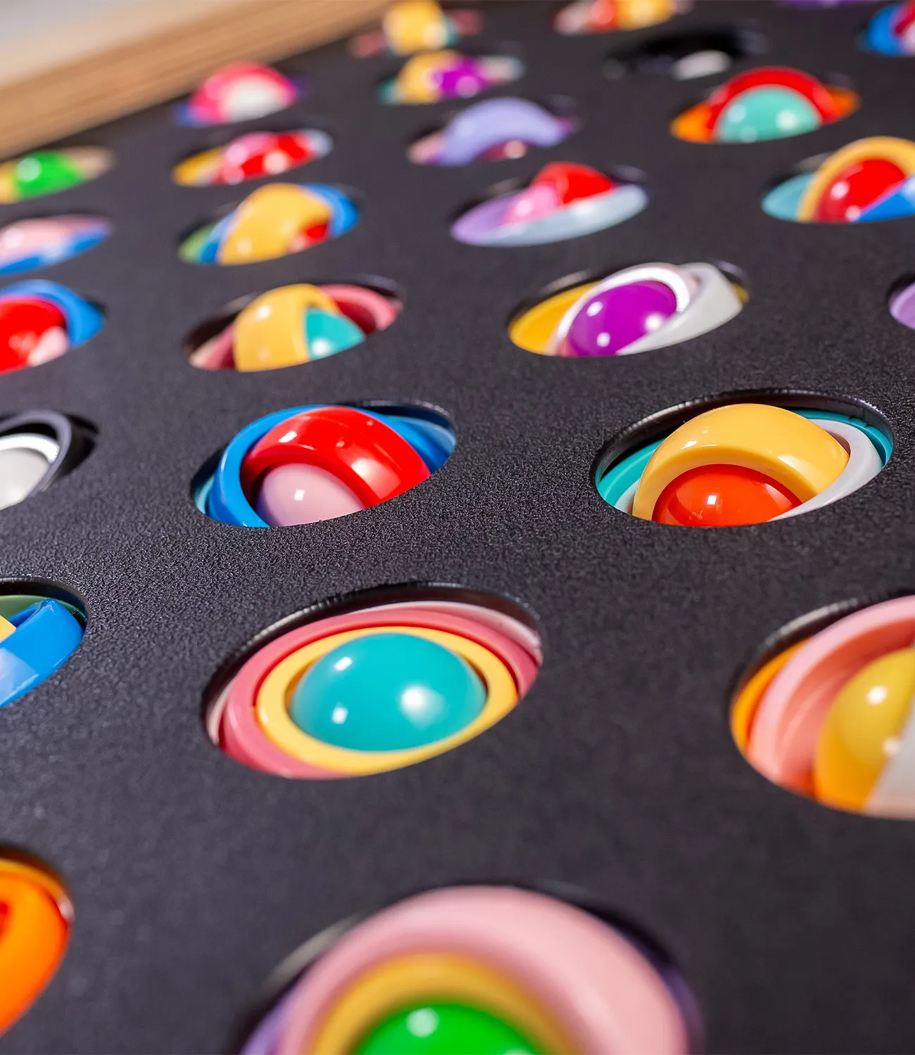 gyro-rings-1 | LiteZilla Colorful swirled lollipops resting in a black baking tray with circular holes.